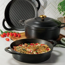 Black enamel cast iron cookware set with two covered pots and a skillet, outdoors scene