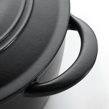 Black enamel cast iron pot with curved handle, close-up