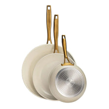 Stacked cream fry pans with gold handles and ceramic interiors
