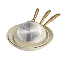Cream fry pan set with ceramic interior and gold handles, three stacked pans