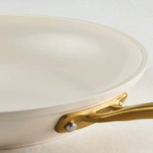 Cream fry pan rim and gold handle with rivet detail
