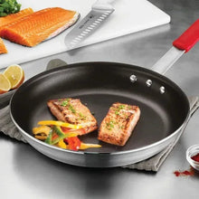 Nonstick restaurant fry pan with black interior, two seared pieces and vegetables