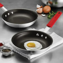 Two 8-inch nonstick fry pans with red handles, one holding a sunny-side egg