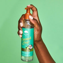 Hand holding Tree Hut moisturizing shave oil bottle with orange pump, green coconut lime label