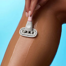 Shaving razor gliding on a leg with shaving product foam, close-up