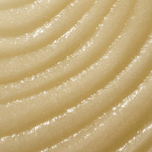 Cream shea sugar scrub swirled on skin, fine sugar granules visible