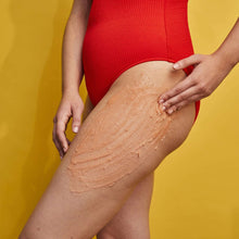 Orange shea sugar scrub spread on leg skin by hands, smooth exfoliating layer