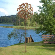 Tri-metallic wind spinner on tall stake with rust brown flower blades and reflective inlays