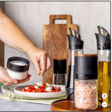 Lazy susan seasoning station with wooden tray, glass spice jars, and black dispensers