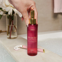 TRULY luxury shave oil bottle with gold pump held by hand, magenta
