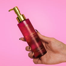 TRULY luxury shave oil bottle with gold pump, magenta, held in hand at angle