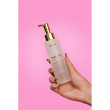 Hand-held Truly Vanilla Baby shave oil bottle with gold pump, white bottle