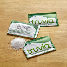 Stevia leaf sweetener packets with sugar crystals on a wooden surface