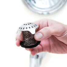 Stainless steel drain strainer and black base held in hand near tub
