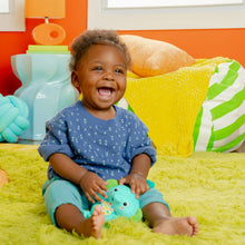Baby playing with teal elephant clip-on plush toy on activity mat