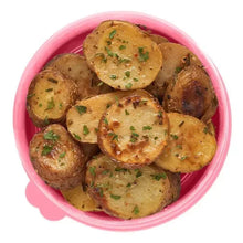 Pink meal prep container filled with cooked potato slices topped with herbs