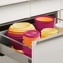 Stacked food storage containers in orange, magenta, and pale yellow inside drawer