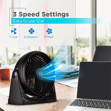 Black desk fan with spinning grille and airflow streaming across a desk