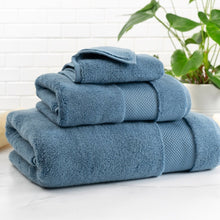Blue bath towel stack in Turkish cotton, folded with a rolled top and textured weave