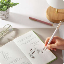 Felt tip pen held to write on notebook; pink pen with gold cap details