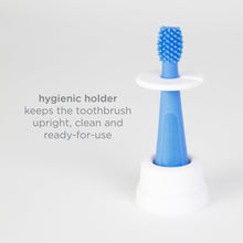 Blue silicone training toothbrush in a hygienic white holder, upright and ready