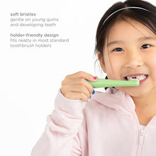 Green toddler training toothbrush with soft bristles, held by a smiling child