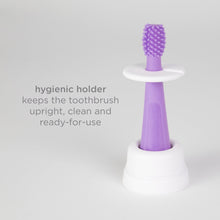 Purple toddler training toothbrush mounted on a white hygienic stand with bristle head up