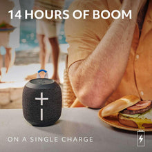 Black wireless Bluetooth speaker on tabletop with cross icon, compact portable design