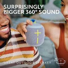 Gray wireless Bluetooth speaker with blue top trim, cross icon on front