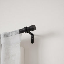 Matte black wall-mount bracket with curtain rod and round finial