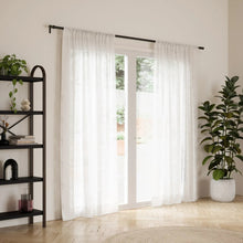 Black curtain rod with sheer white curtains installed and two end supports