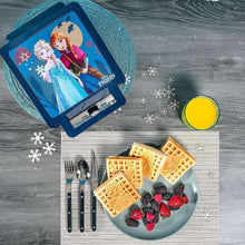 Frozen waffle maker with open lid, waffles on plate with berries and cutlery