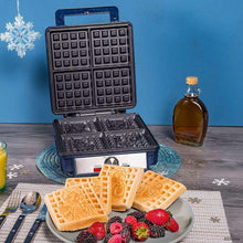 Open waffle maker with black grids, waffles on plate topped with berries