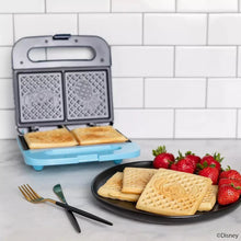 Blue Stitch waffle maker with open plates, two browned square waffles visible