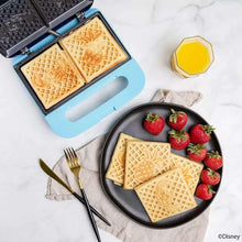Stitch-themed blue waffle maker open to square plates, waffles on a tray with fruit