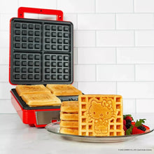 Red waffle maker open with patterned plates and golden waffle squares