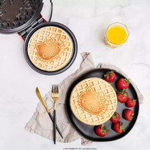 Opened Hello Kitty waffle maker showing embossed Hello Kitty waffles and strawberries