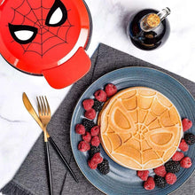 Cooked Spiderman waffle with web pattern, berries, and syrup in tray