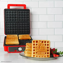 Open waffle maker showing black grid plates with golden character waffles