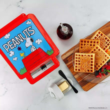 Peanuts-themed waffle maker with golden waffles on a wooden serving board