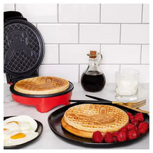 Round waffle maker with red base and black plates, showing golden waffles