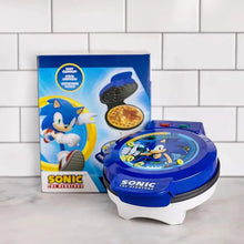 Blue Sonic waffle maker on base with open lid beside product box