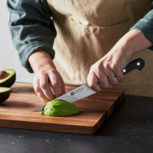 6-inch utility knife with silver blade and black handle, held while cutting