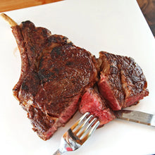Sliced grilled steak with herbs on a white cutting board