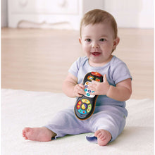 Toddler holding an orange and black number keypad remote toy with colorful buttons