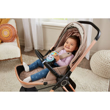 Baby in stroller holding the plush hippo soft phone toy