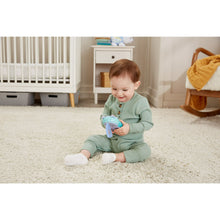 Baby sitting on carpet holding the plush hippo soft phone toy