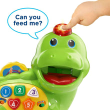 Close-up of green dinosaur toy mouth opening with hand offering a piece