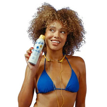 SPF 50 sunscreen spray bottle held by person in blue bikini
