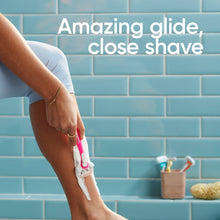 Women's leg being shaved with a pink and white 3-blade disposable razor